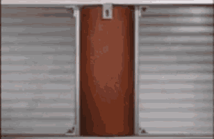 a red pipe is hanging from the side of a metal wall .