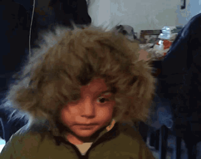 a little boy wearing a furry hooded jacket looks at the camera