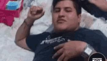 a man is laying on a bed with his eyes closed and his hands on his chest .