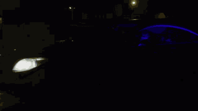 a car is parked in the dark with the headlight on