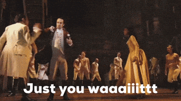 a group of people are dancing on a stage and the words just you waaaiiittt are on the bottom of the image