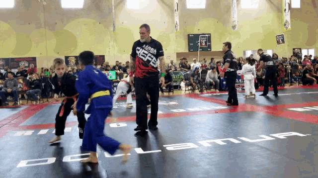 a man wearing a shirt that says defend is standing on a wrestling mat