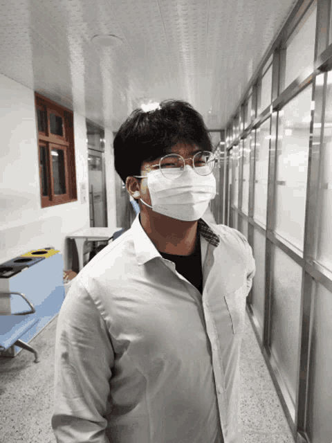 a man wearing a mask and glasses is standing in a hallway