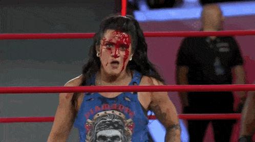 a wrestler with blood on her face is in a ring .