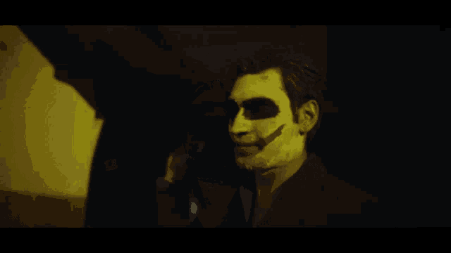 a man with a skull painted on his face stands in a dark room