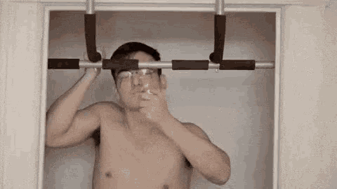 a shirtless man is doing pull ups on a bar in a doorway .