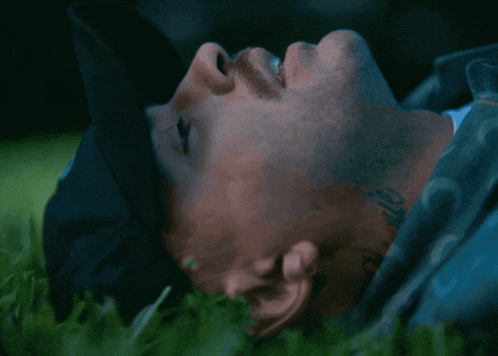 a man with a tattoo on his neck is laying on the grass