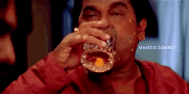 a man is drinking a glass of whiskey .