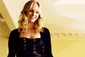 a woman in a black dress is smiling and looking at the camera .