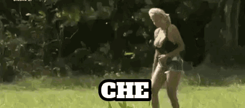 a woman in a black top and shorts is standing in a field with the word che written on the bottom .