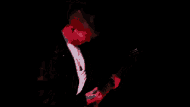 a blurry picture of a man playing a guitar in a dark room .