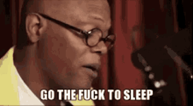 a man wearing glasses and a yellow shirt is talking into a microphone and saying `` go the fuck to sleep '' .