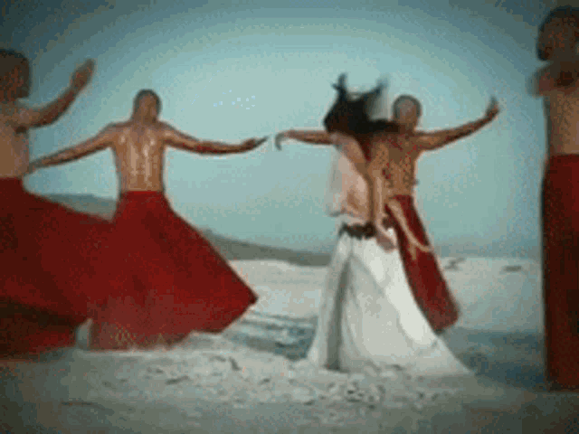 a group of people in red skirts and white dresses are dancing in the sand