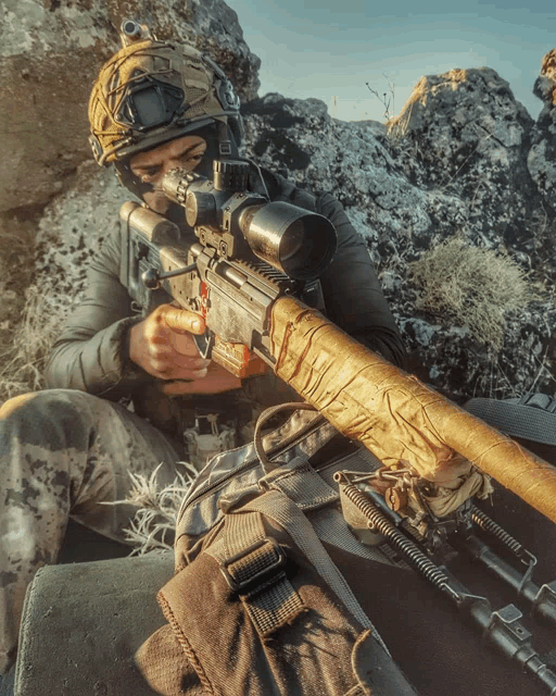 a soldier is holding a sniper rifle with a scope on it