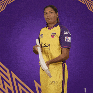 a woman wearing a yellow and purple shirt with kay beauty on it