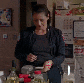 a woman is smiling while looking at her cell phone in front of a refrigerator that says nbc on it