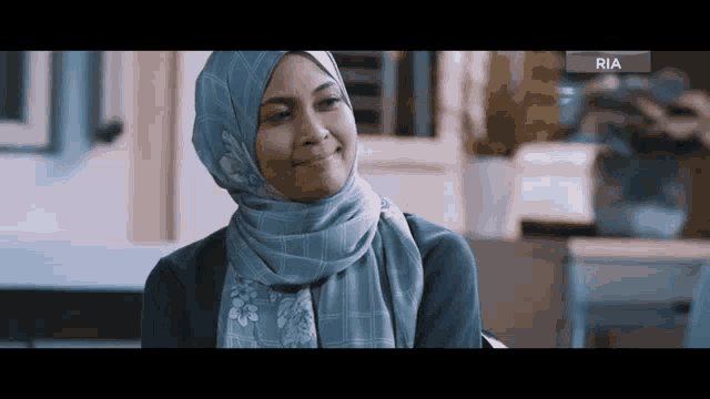 a woman wearing a hijab and a scarf is smiling in a kitchen