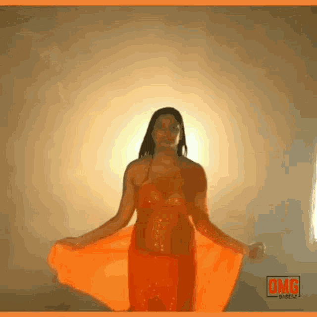 a woman in a red dress is dancing in front of an omg sign