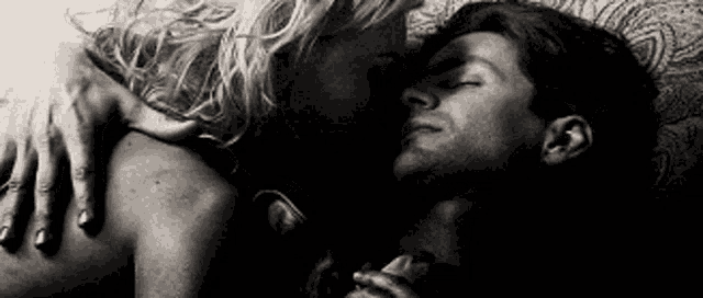 a man and a woman are laying on a bed and hugging each other .