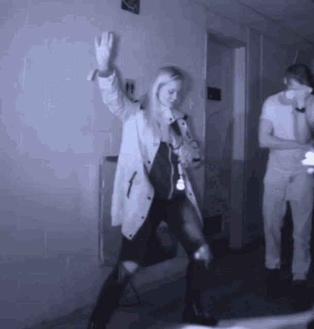 a woman in a white coat is dancing in a hallway with a man in a white shirt .