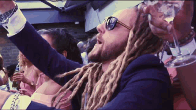 a man with dreadlocks is holding a glass in his hand