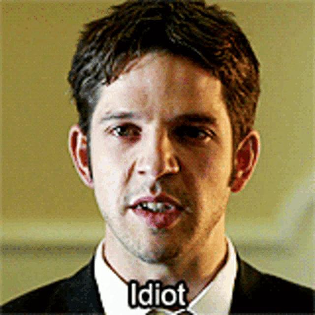 a man in a suit and tie with the word idiot on his face