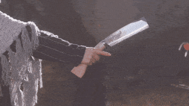 a woman in a sweater and scarf holds a large knife