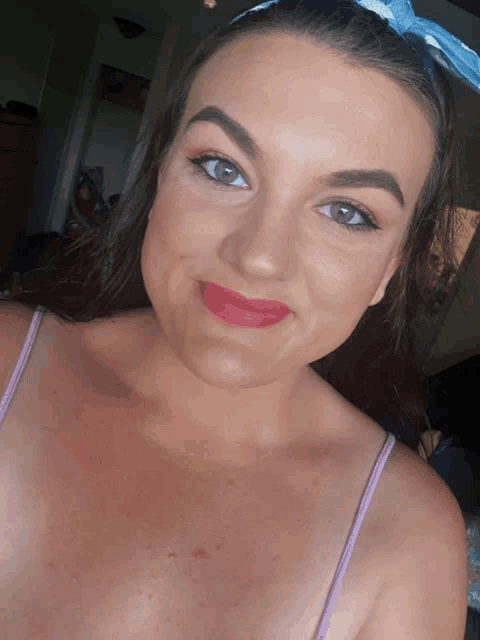 a woman wearing a headband and red lipstick smiles at the camera