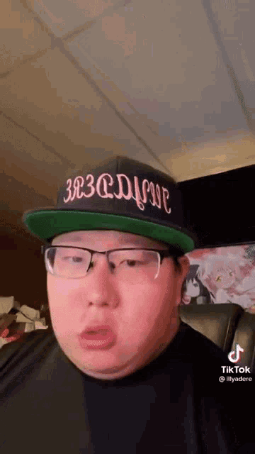 a man wearing glasses and a hat is sitting in a chair .