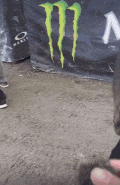 a person standing in front of a monster energy drink banner