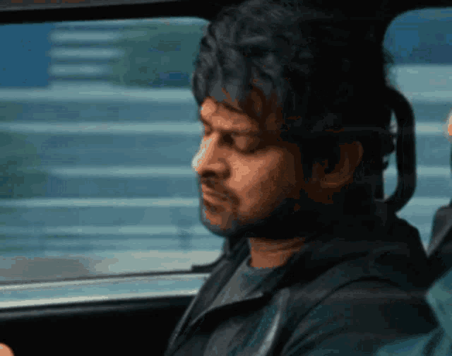a man is sitting in a car looking out the window