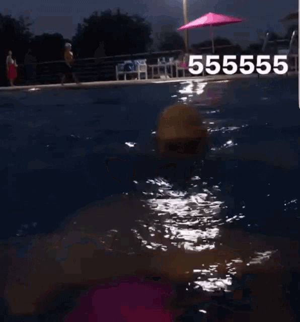 a man wearing a pink swim cap and goggles is swimming in a pool with the number 55555 above him