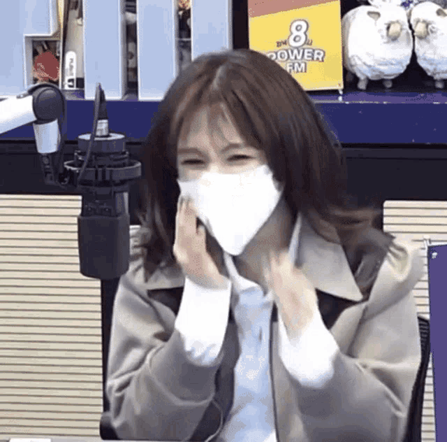 a woman wearing a mask is sitting in front of a microphone in a studio .