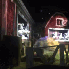 a blurred image of a red barn at night with a fence in front of it