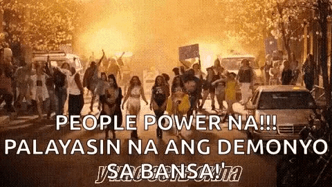 a group of people are walking down a street with a sign that says people power na !!!