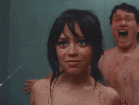 a woman with blood on her face is smiling while a man with blood on his face screams in the background
