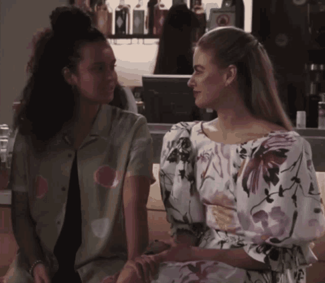 a woman in a floral dress sits next to another woman in a polka dot shirt