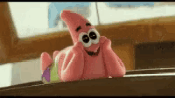 a stuffed animal of patrick star from spongebob squarepants is laying down on a table .