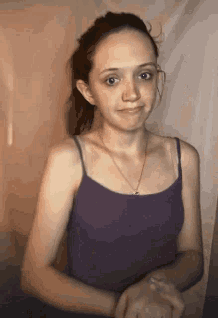 the girl is wearing a purple tank top and a gold necklace .