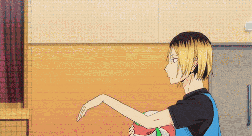 a man is holding a volleyball in his hand and playing volleyball in a gym .