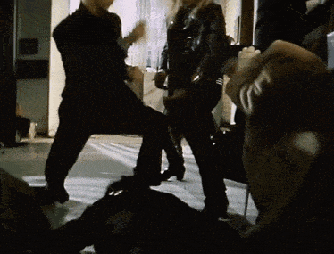 a man in a black jacket is kneeling down in front of a woman