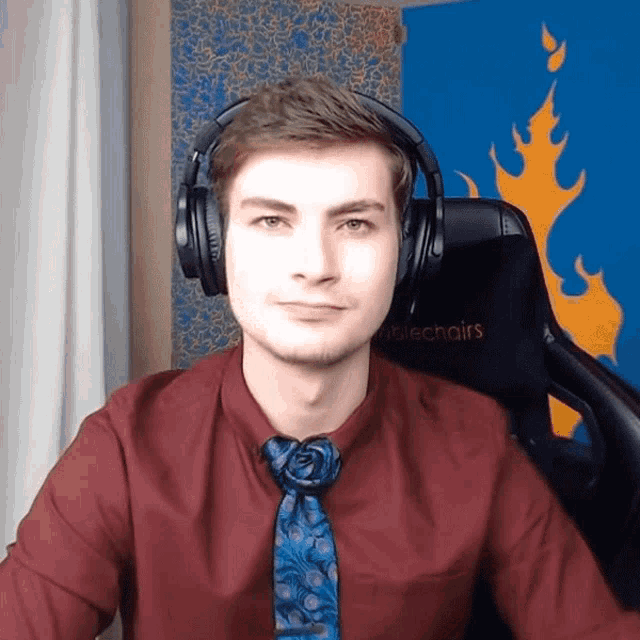a man wearing headphones and a red shirt is sitting in a chair that says noblechairs