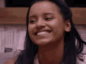 a close up of a woman 's face smiling and looking at the camera .