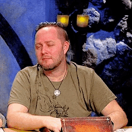 a man sitting at a table with his eyes closed and a necklace around his neck