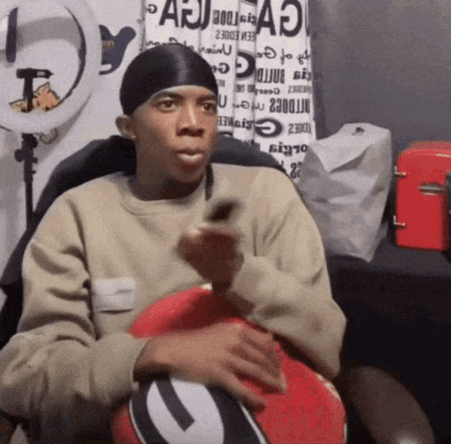 a man is sitting in a chair holding a remote control in front of a sign that says ' a ' on it