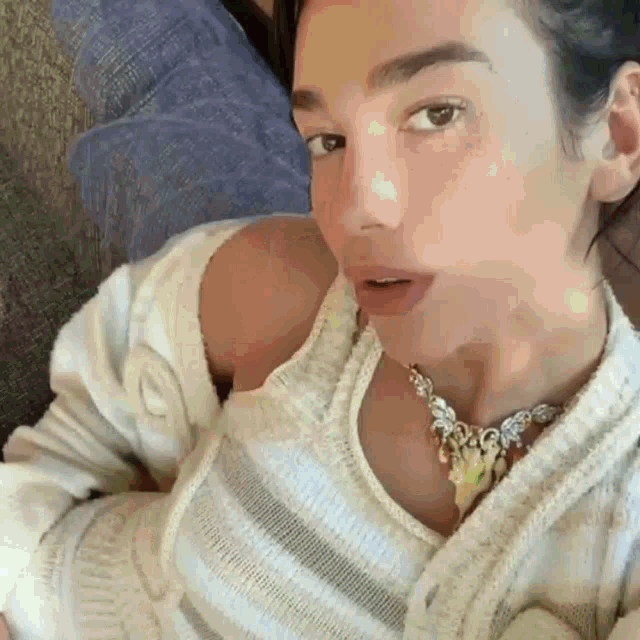 a close up of a woman wearing a sweater and a necklace .