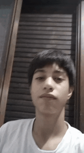 a young man is taking a selfie in front of a wooden shutter .
