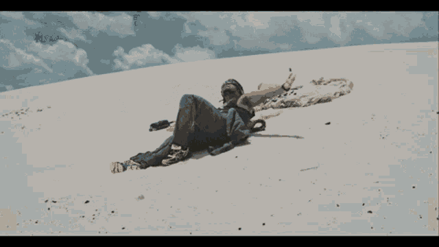 a person laying on the sand with their arms outstretched