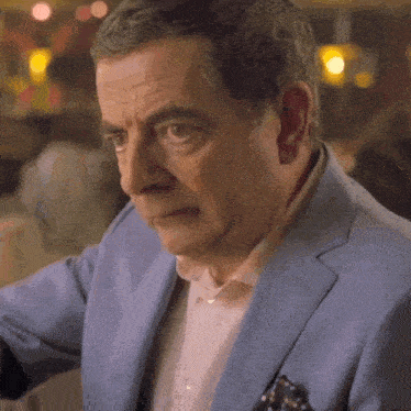 a man wearing a blue suit and a white shirt is looking at something