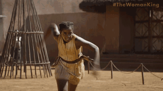 a woman is running in a field with #thewomanking written on the bottom right